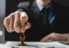 Green Cards Slump – What Got Tightened? Hand stamping a document on a desk