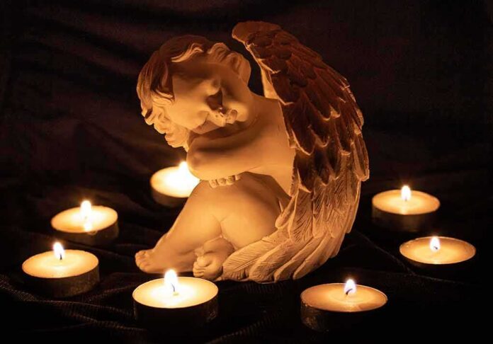 shutterstock_1887132472 angel statue surrounded by lit candles