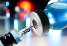 Syringe needle entering a vaccine vial
