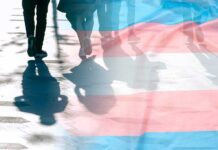 Tax Dollars Fund Youth Hormones – Despite Bans trans pride flag overlaying silhouettes of people walking on a city street