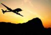 Drone silhouette flying over mountains at sunset
