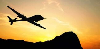 Drone silhouette flying over mountains at sunset