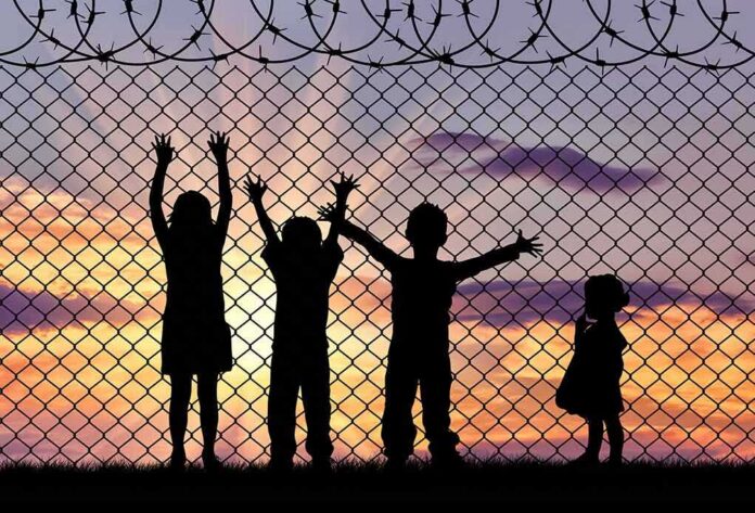 shutterstock_369286484 Children silhouetted against a chain-link fence at sunset