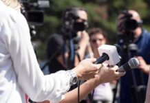 Reporters hold microphones during an outdoor press interview
