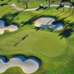 Bipartisan Retreat – At Trump’s Place? Golfers on a green surrounded by sand bunkers