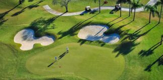 Golfers on a green surrounded by sand bunkers